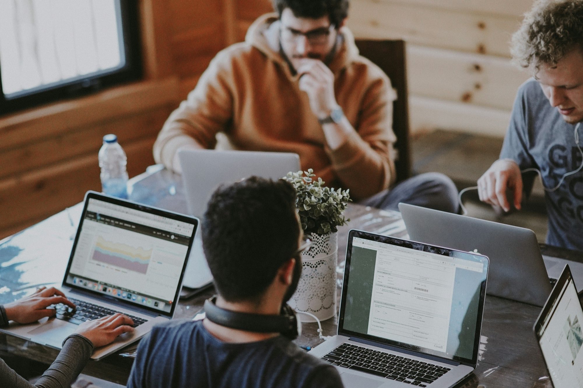 A team working together on laptops around a wooden table